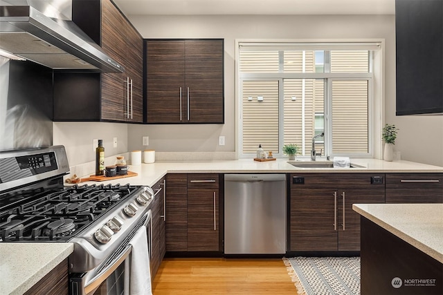 kitchen featuring stainless steel appliances, dark brown cabinets, sink, and wall chimney exhaust hood