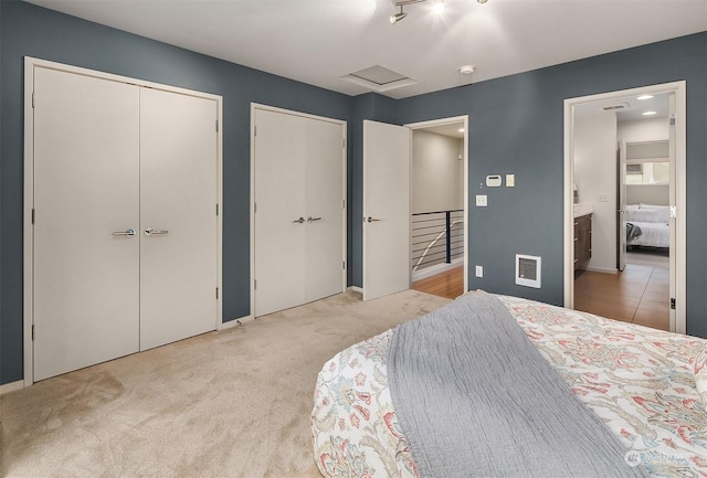 carpeted bedroom featuring connected bathroom and two closets