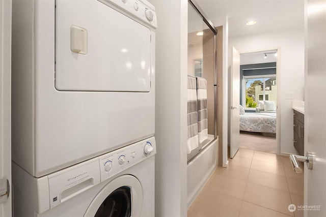 laundry area featuring light tile patterned floors and stacked washing maching and dryer