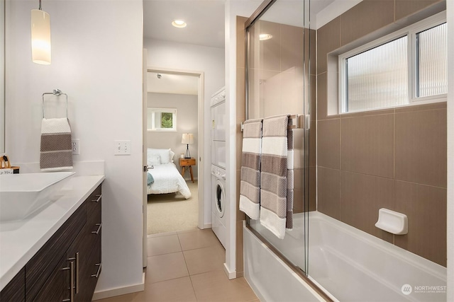 bathroom featuring stacked washer and dryer, vanity, combined bath / shower with glass door, and tile patterned flooring