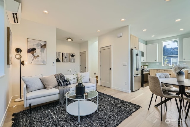 living area featuring recessed lighting, baseboards, a wall mounted AC, and light wood finished floors