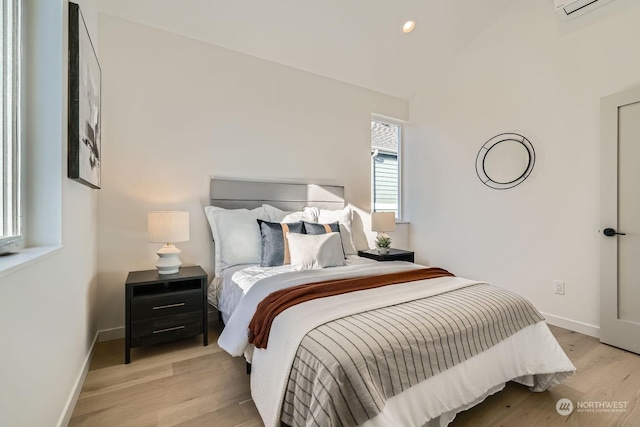 bedroom featuring lofted ceiling, an AC wall unit, light wood-style flooring, recessed lighting, and baseboards