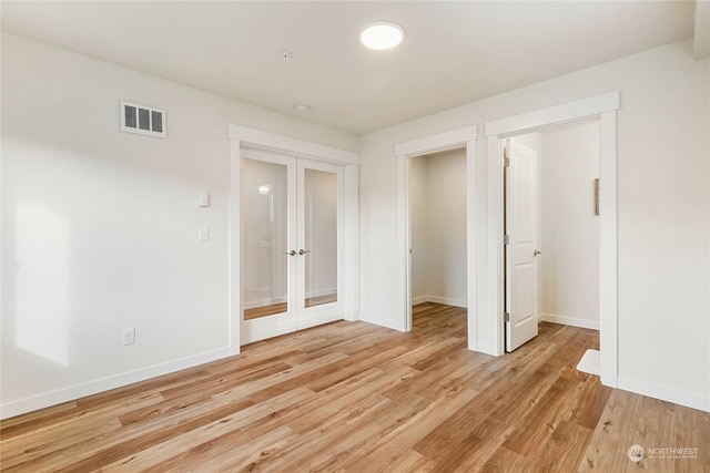 unfurnished bedroom featuring a closet, light hardwood / wood-style floors, and french doors