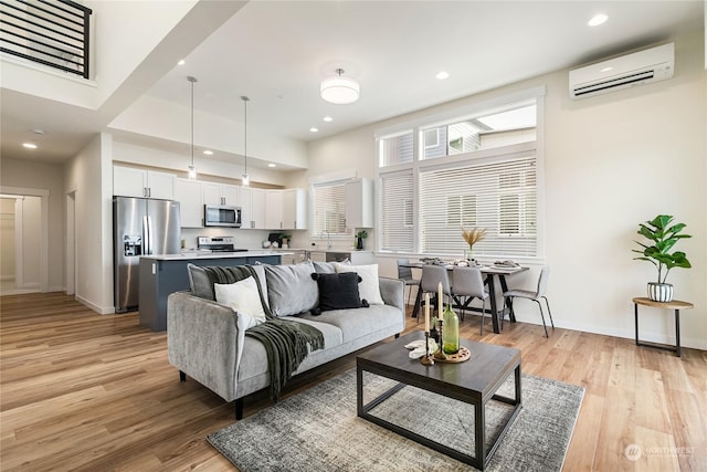 living room with sink, light hardwood / wood-style flooring, and an AC wall unit