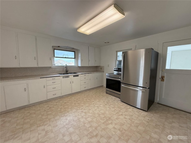 kitchen featuring stainless steel appliances, white cabinetry, sink, and tasteful backsplash