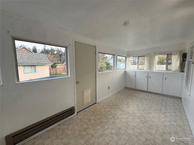 unfurnished sunroom with plenty of natural light and a baseboard heating unit