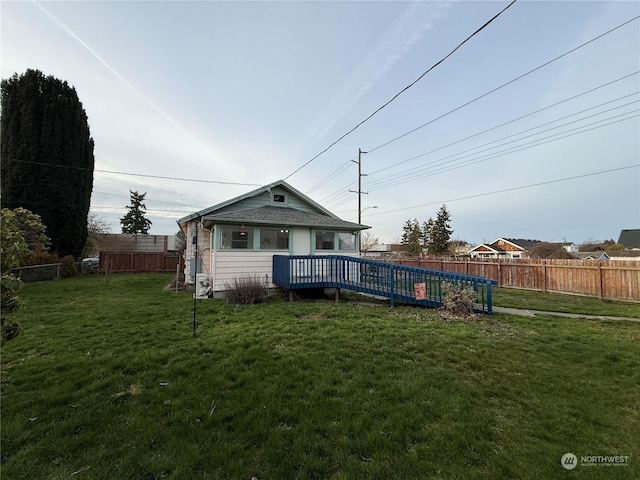 rear view of property featuring a deck and a lawn