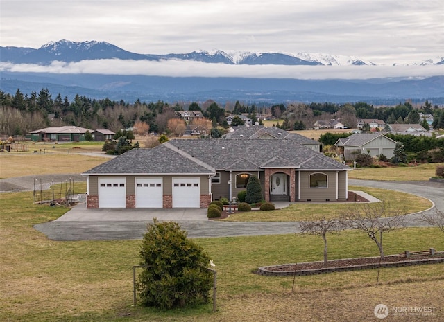 view of front facade featuring a garage, driveway, a front lawn, and a mountain view