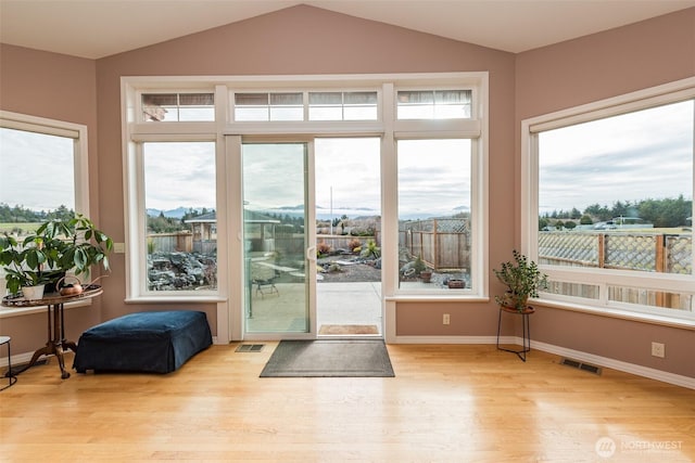 doorway to outside with lofted ceiling, light wood-style flooring, visible vents, and baseboards