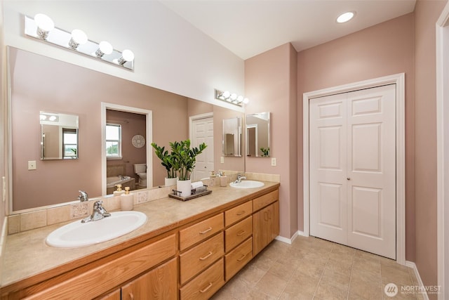 full bathroom featuring a sink, double vanity, toilet, and a closet