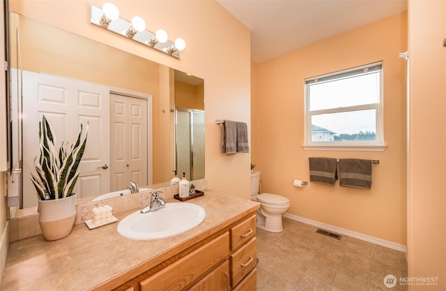 bathroom with toilet, visible vents, vanity, baseboards, and a stall shower