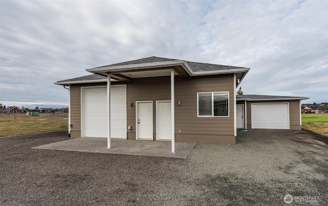 view of front of home featuring gravel driveway, roof with shingles, and fence