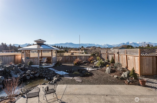 view of yard featuring a gazebo, a fenced backyard, and a mountain view