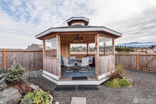 wooden terrace with a fenced backyard, a mountain view, outdoor dining area, and a gazebo