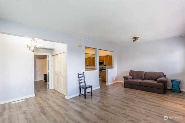 living area with baseboards, a chandelier, and light wood-style floors