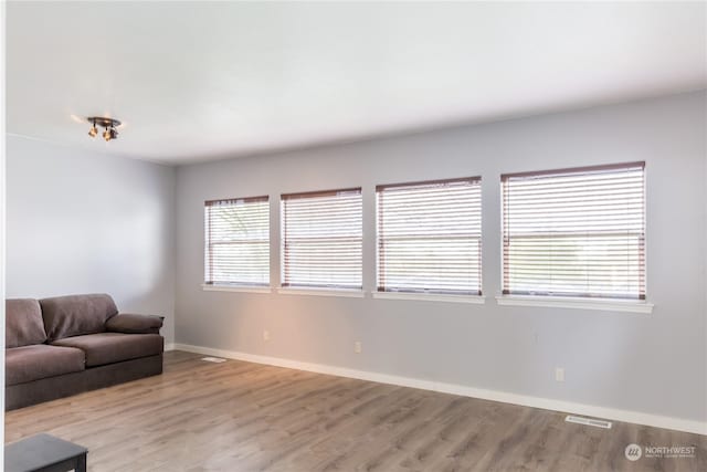 unfurnished living room featuring light wood-style flooring, visible vents, and baseboards