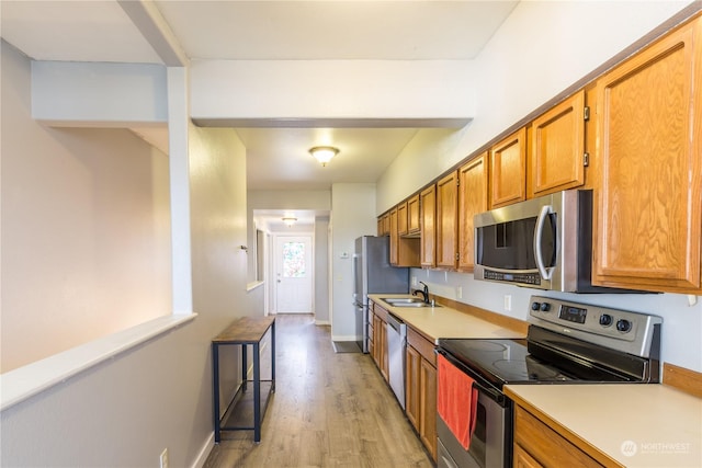 kitchen featuring appliances with stainless steel finishes, brown cabinets, light countertops, and a sink