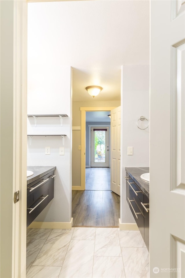 interior space featuring marble finish floor, baseboards, and vanity