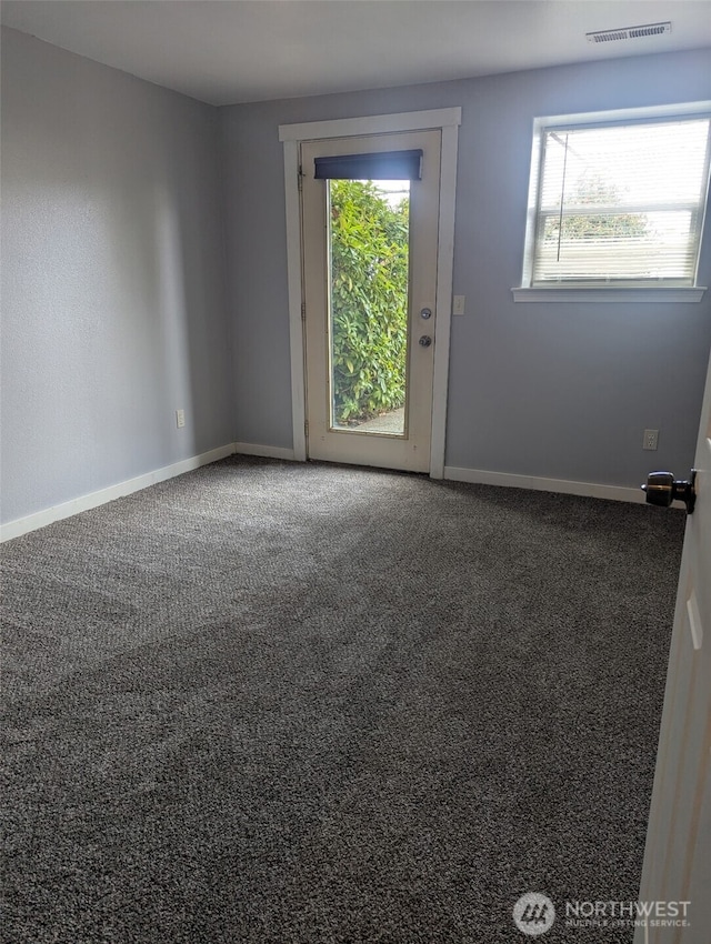 empty room featuring carpet floors, visible vents, plenty of natural light, and baseboards