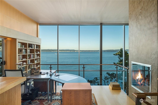 home office featuring a water view, wood-type flooring, and floor to ceiling windows