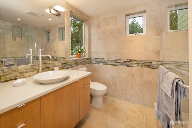 bathroom with tile walls, vanity, toilet, and tile patterned floors