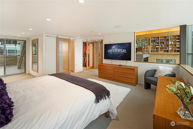 bedroom featuring access to outside, light colored carpet, and a barn door