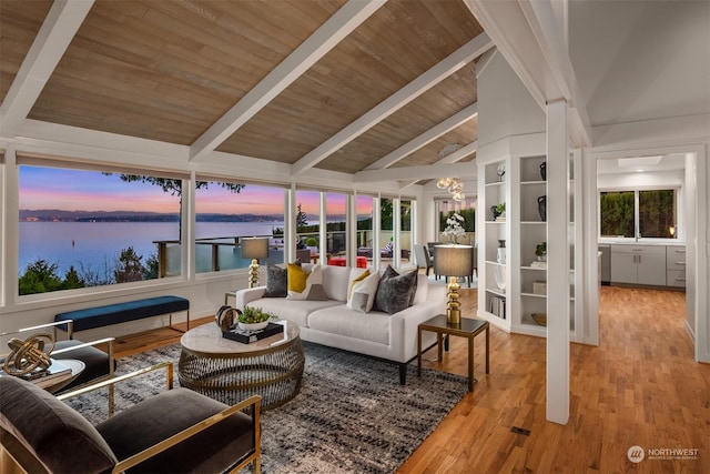 sunroom / solarium with vaulted ceiling with beams, wooden ceiling, and a water view