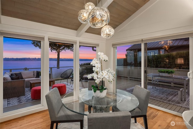 sunroom featuring a water view, lofted ceiling, wood ceiling, and an inviting chandelier