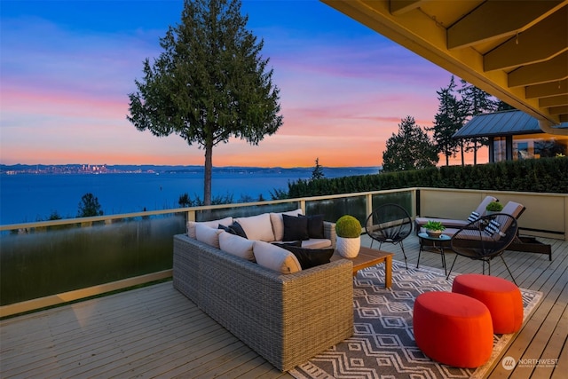 deck at dusk with a water view and an outdoor hangout area