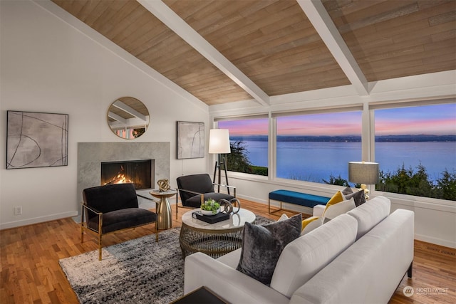 living room featuring hardwood / wood-style floors, lofted ceiling with beams, wood ceiling, a premium fireplace, and a water view