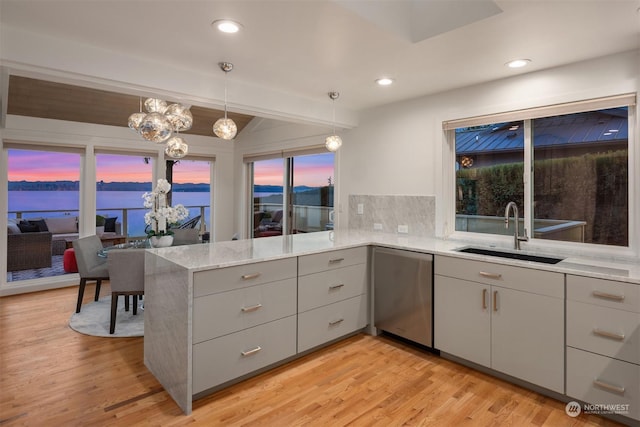 kitchen with sink, a water view, tasteful backsplash, stainless steel dishwasher, and kitchen peninsula