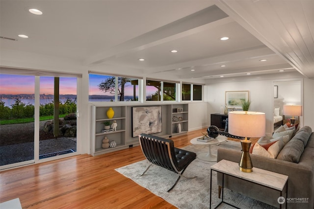 living room featuring built in features, light hardwood / wood-style floors, and beamed ceiling