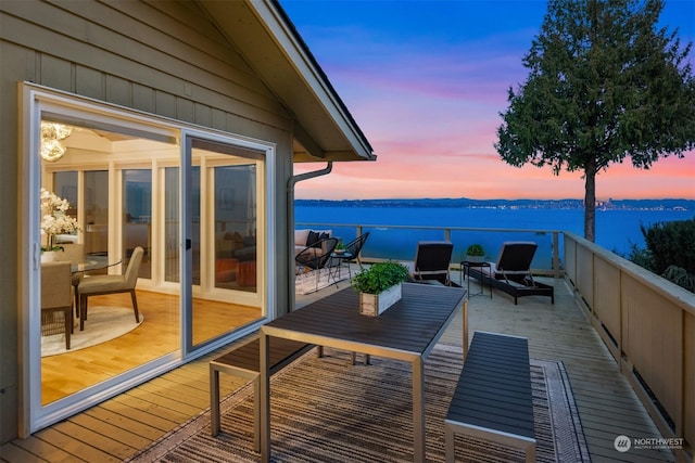 balcony at dusk featuring a water view