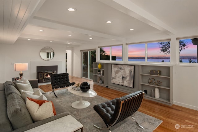 living room featuring built in shelves, beam ceiling, and light hardwood / wood-style floors