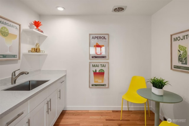 kitchen featuring white cabinetry, sink, and light hardwood / wood-style flooring