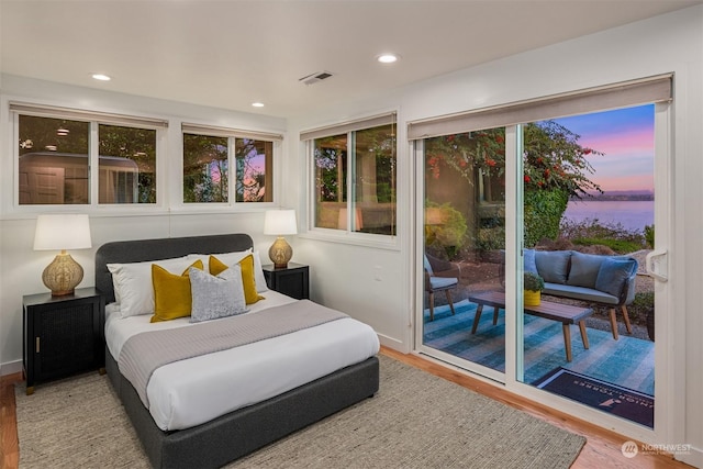 bedroom with access to exterior and hardwood / wood-style flooring