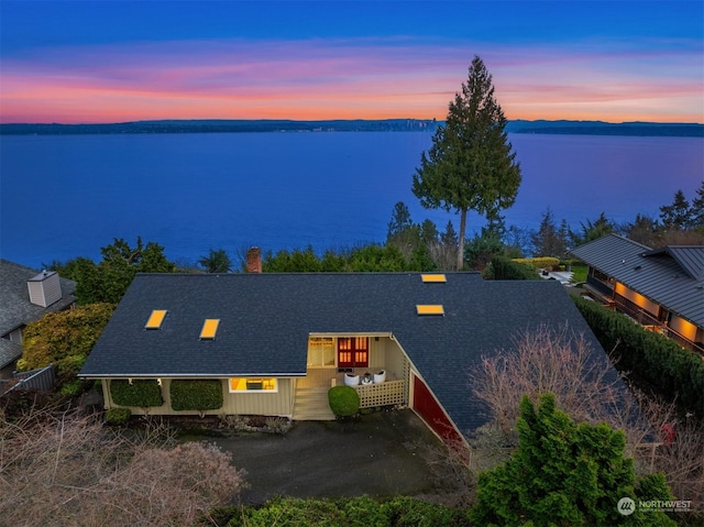 aerial view at dusk featuring a water view