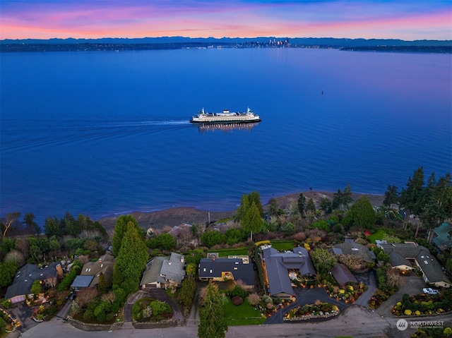 aerial view at dusk featuring a water view