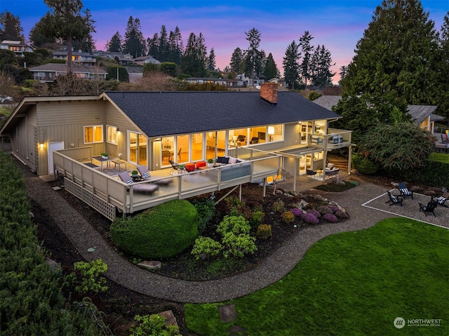 back house at dusk featuring a yard, a patio, a balcony, and an outdoor fire pit