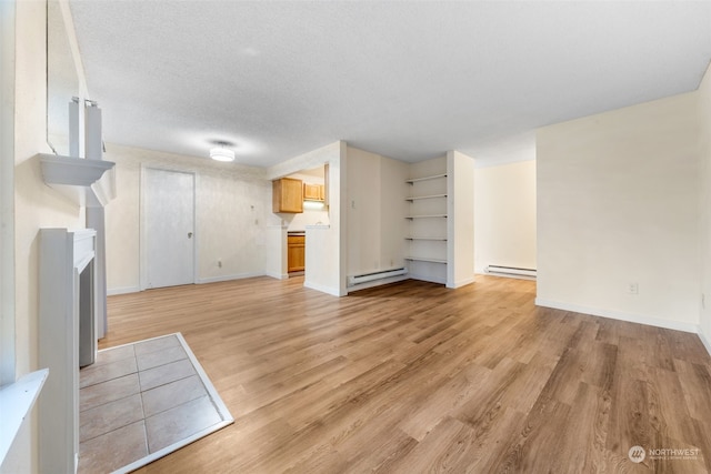 unfurnished living room with light hardwood / wood-style flooring, a textured ceiling, and baseboard heating