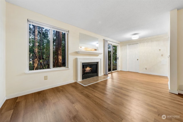 unfurnished living room with a textured ceiling and light hardwood / wood-style floors