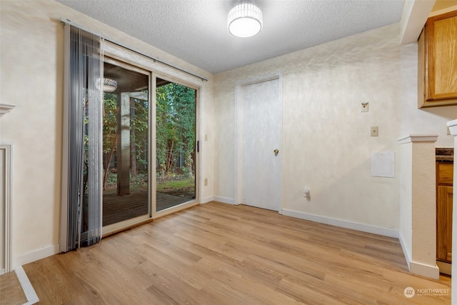 unfurnished dining area with light hardwood / wood-style flooring and a textured ceiling