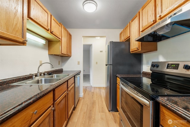 kitchen with dark stone countertops, sink, light hardwood / wood-style flooring, and stainless steel appliances