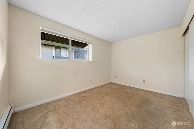 empty room featuring a baseboard radiator, light carpet, and a textured ceiling