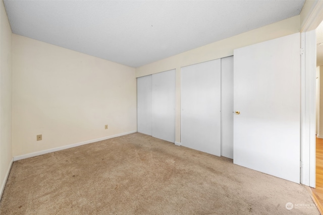 unfurnished bedroom featuring multiple closets and light carpet