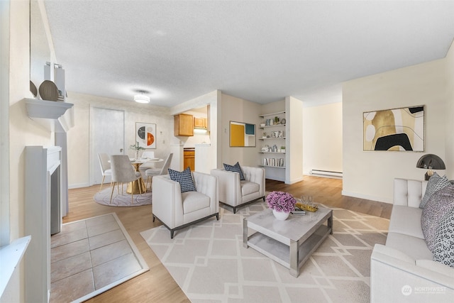 living room with a baseboard heating unit, a textured ceiling, and light wood-type flooring