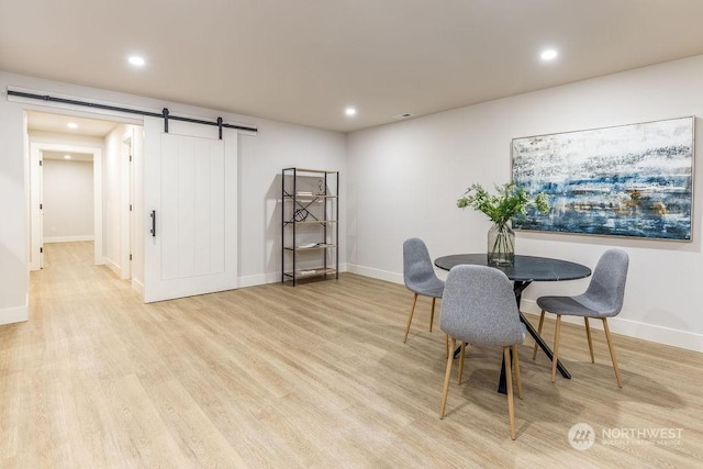 dining space featuring a barn door and light wood-type flooring