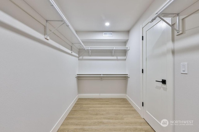 walk in closet with light hardwood / wood-style floors