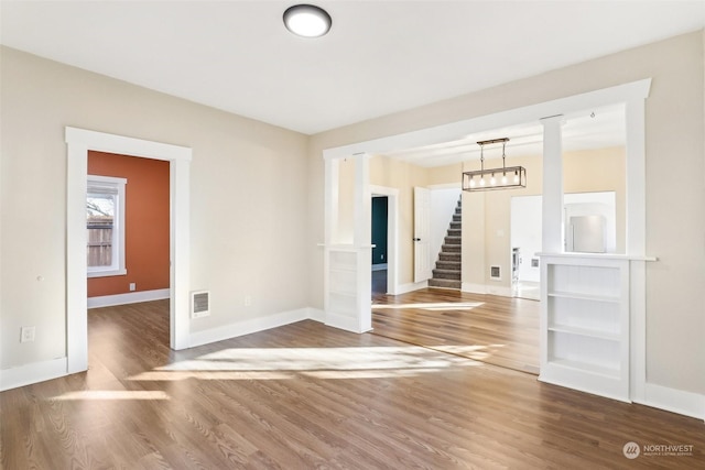 unfurnished room with wood-type flooring and a chandelier