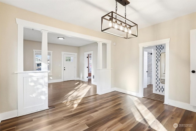 unfurnished dining area with dark wood-type flooring and ornate columns